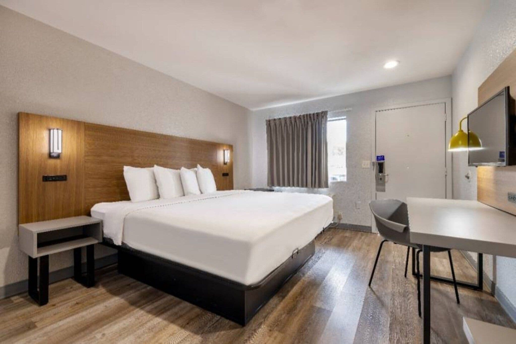 A hotel room with a large bed, bedside tables, a desk, and a chair.