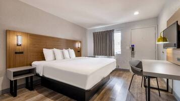 A hotel room with a large bed, bedside tables, a desk, and a chair.
