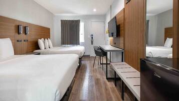 A hotel room with two beds, a desk, a chair, a TV, and a wardrobe.