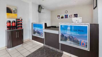 A reception area with a digital screen displaying a cityscape, a clock, and a coffee machine.