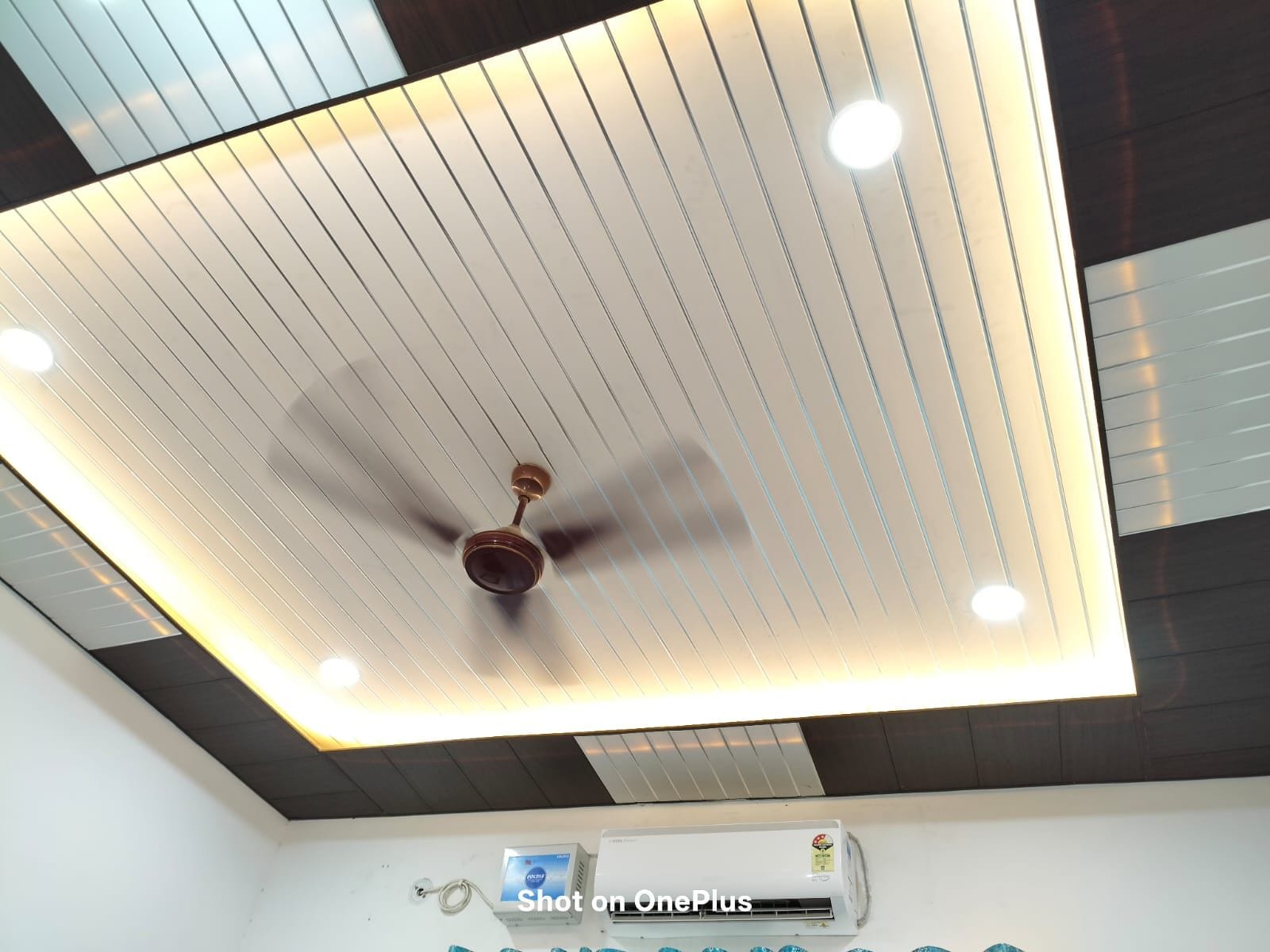 A ceiling with a central fan and recessed lighting.