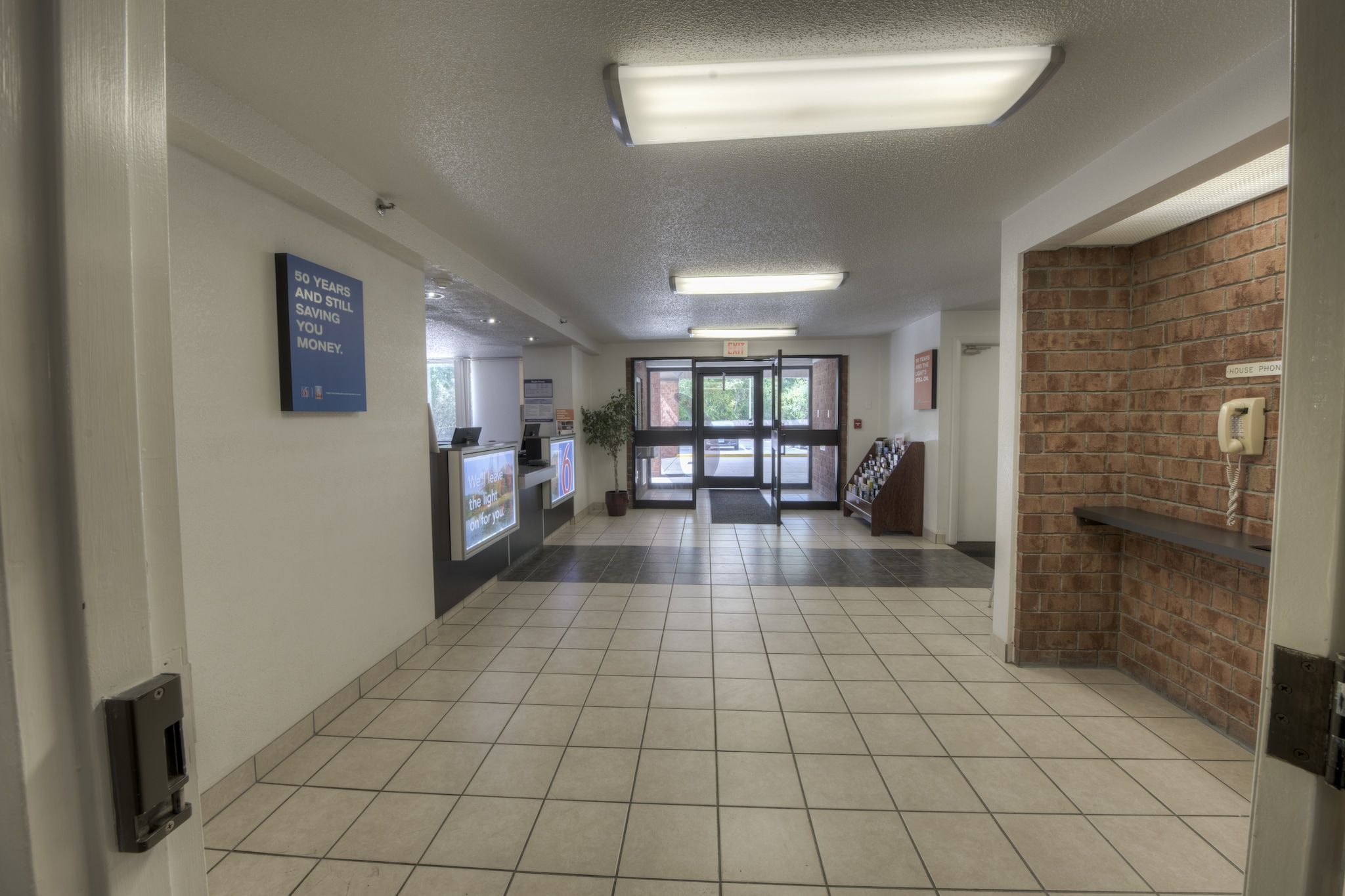A spacious lobby with a reception desk, a sign indicating a 50-year anniversary, and a house phone.