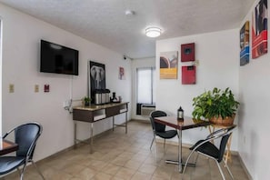A dining area with a table, chairs, a TV mounted on the wall, and a plant on the table. - Comfy King Bed|Free Wifi &Parking (Attalla)