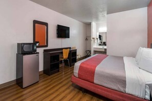 Una camera d'albergo con un letto, una scrivania, una sedia, una televisione e un piccolo frigorifero.