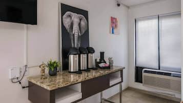 A kitchen with a granite countertop, stainless steel appliances, a potted plant, and a mounted television.