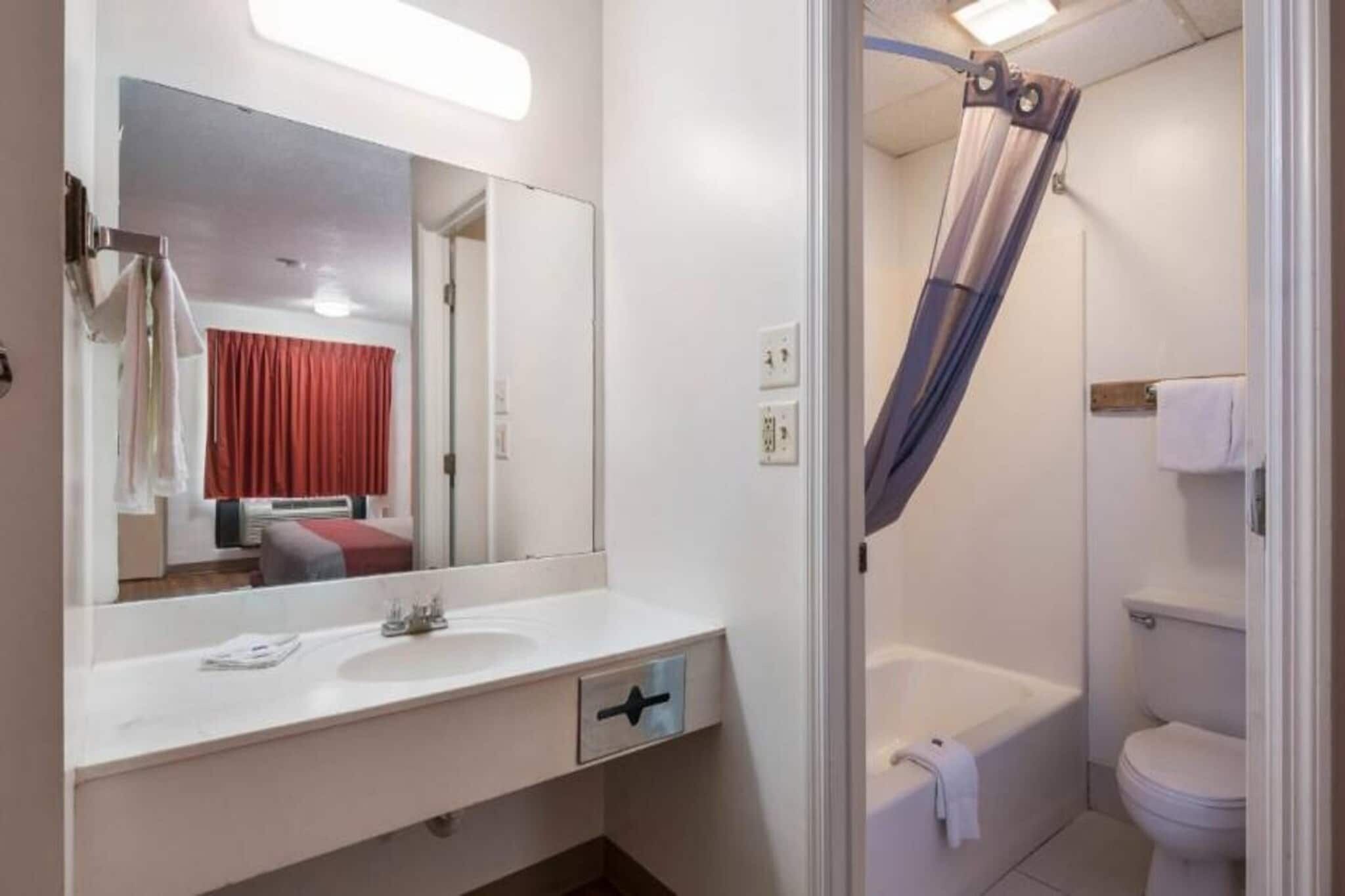 A bathroom with a white sink, mirror, and a shower curtain.