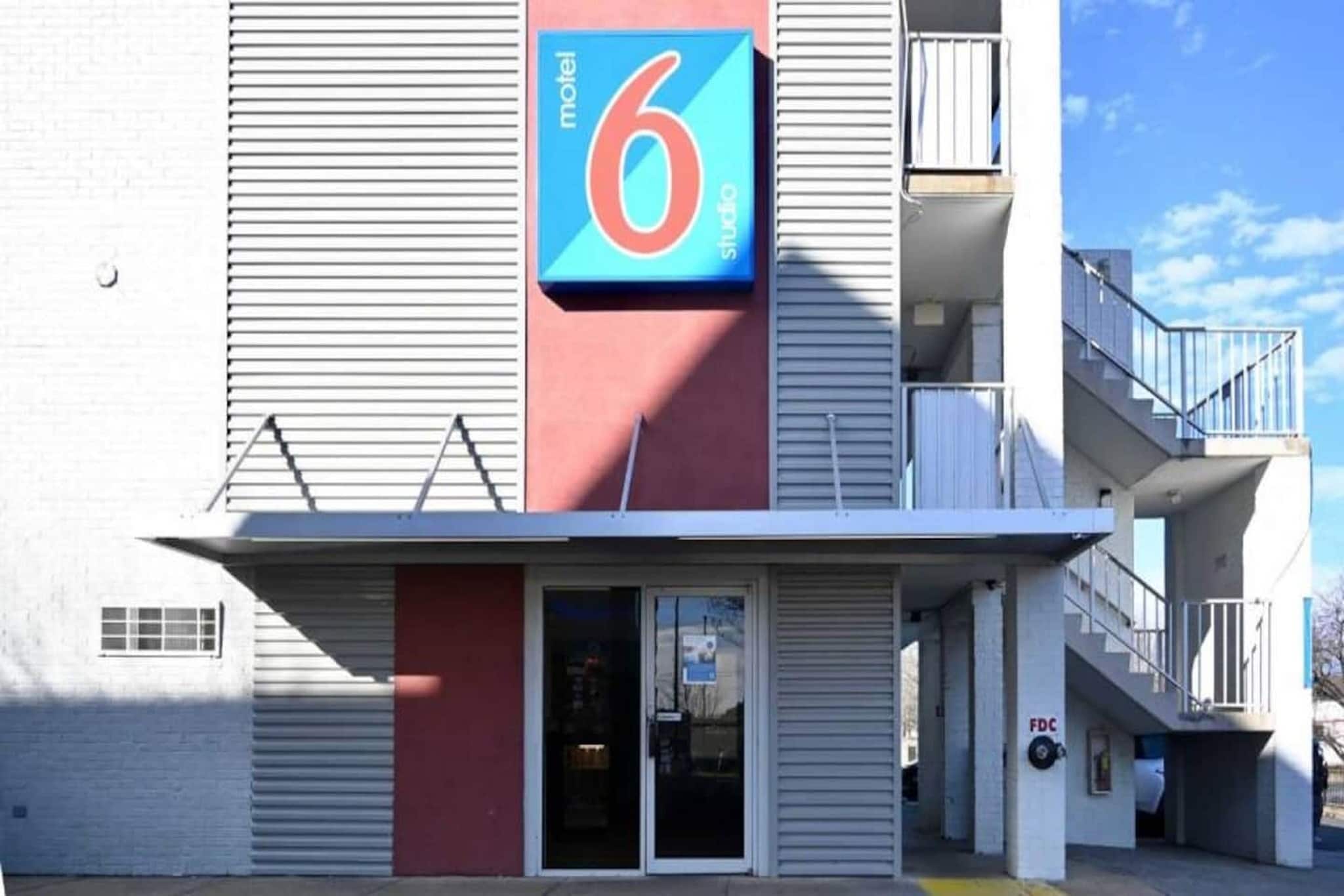 Een gebouw met een opvallend bord met het cijfer '6', een hekwerk en een zichtbare trap die naar een hoger gelegen verdieping leidt.