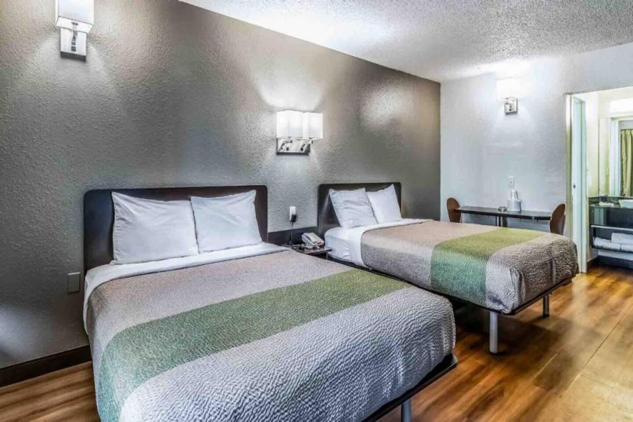 Een hotelkamer met twee bedden, een kleine tafel en een stoel.