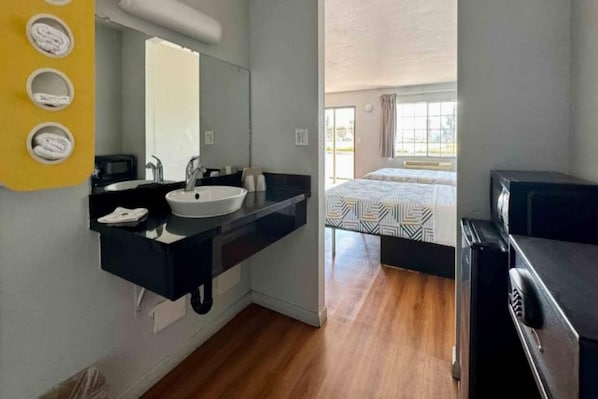 A modern bathroom with a sink, mirror, and towel rack.