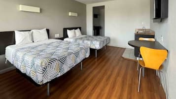 Une chambre d’hôtel avec deux lits, une petite table, une chaise et un téléviseur fixé au mur.