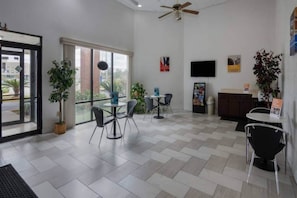 Un interior moderno con zona de comedor, televisor y ventilador de techo.