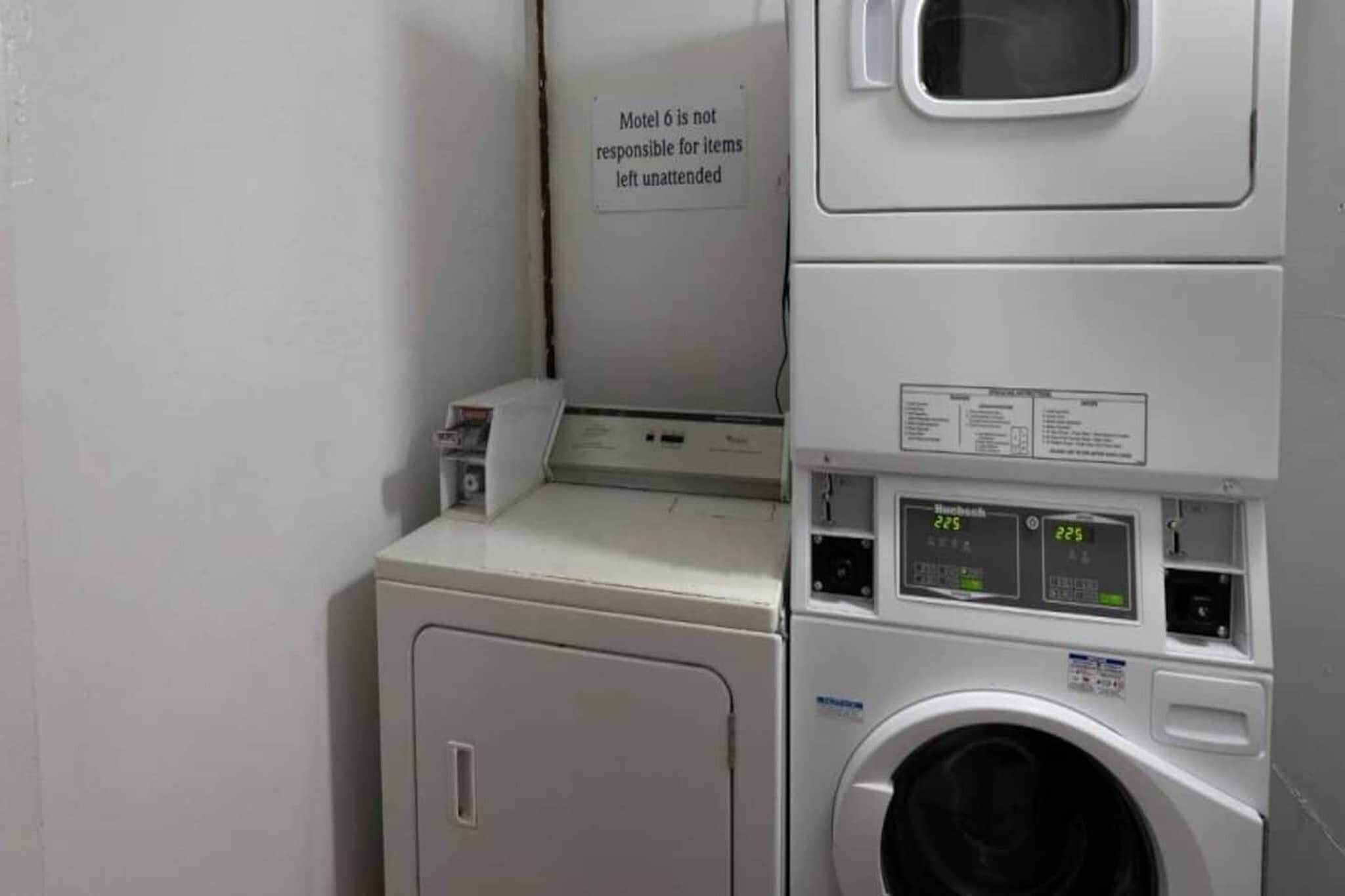 A laundry area with a sign stating 'Motel 6 is not responsible for items left unattended.'
