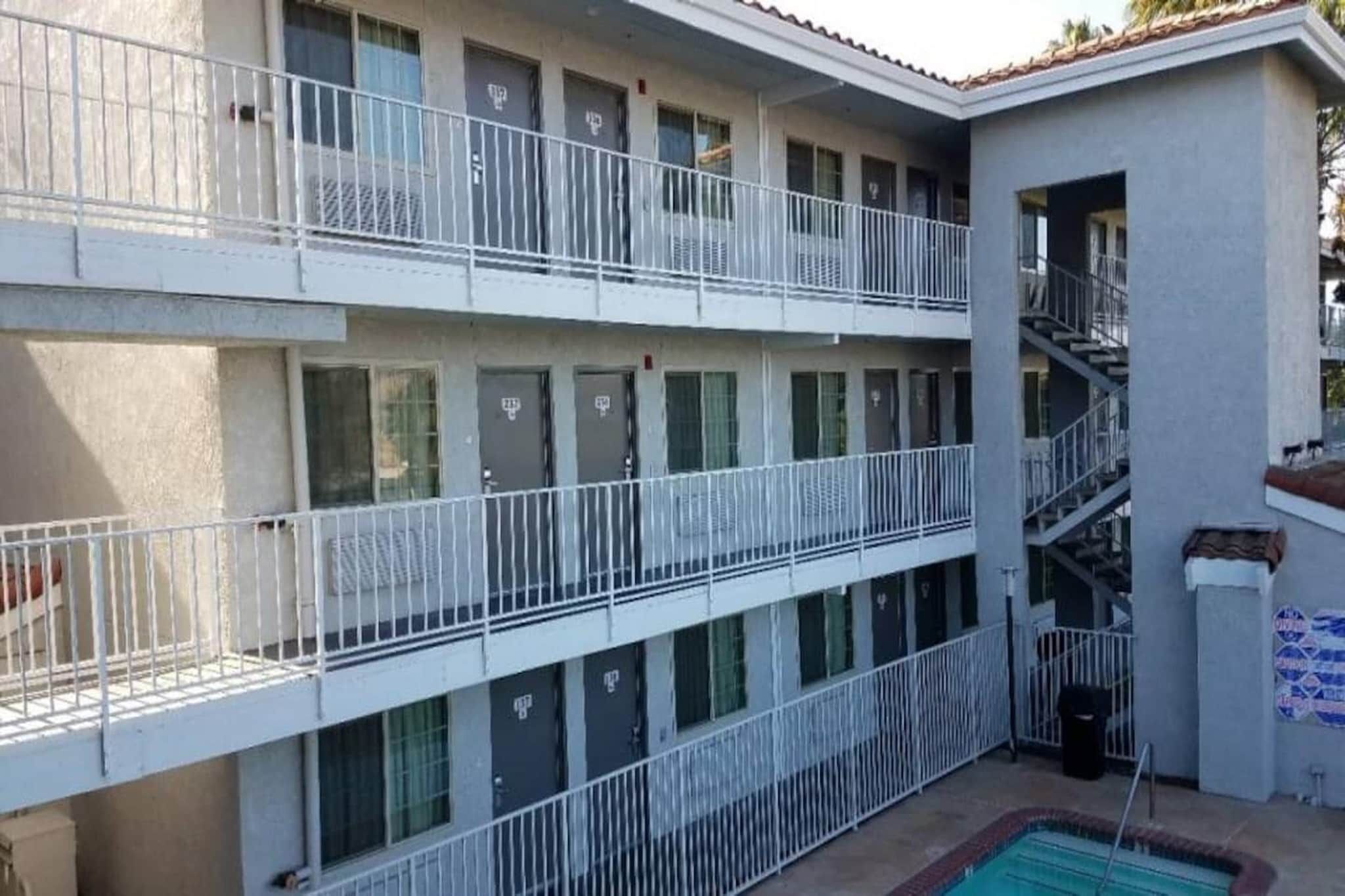 Un immeuble à plusieurs étages doté de balcons, d’une piscine et d’un escalier.