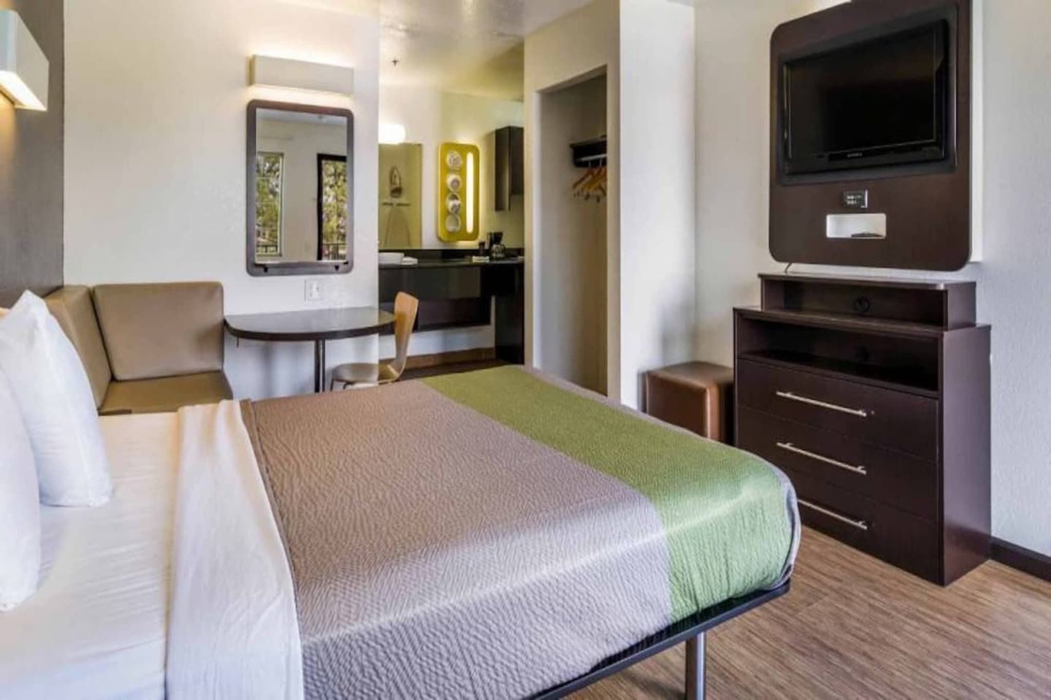 Een hotelkamer met een bed, een bureau, een stoel, een dressoir en een televisie.