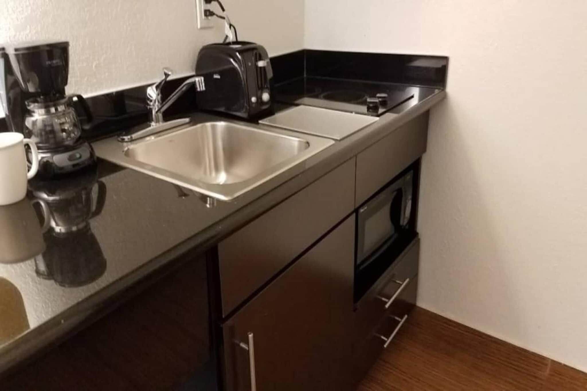 Une petite cuisine équipée d’un évier en acier inoxydable, d’un grille-pain et d’une machine à café.
