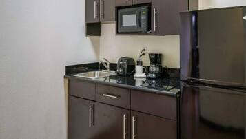 Une cuisine compacte équipée d’un four à micro-ondes, d’un grille-pain, d’une machine à café et d’un réfrigérateur.