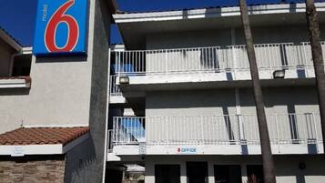 Een motel met een opvallend nummer '6' bord, meerdere balkons en een 'OFFICE' bord dat een bedrijf op de begane grond aangeeft.