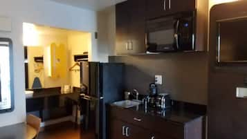 A compact kitchen with a microwave, refrigerator, sink, and cabinets.