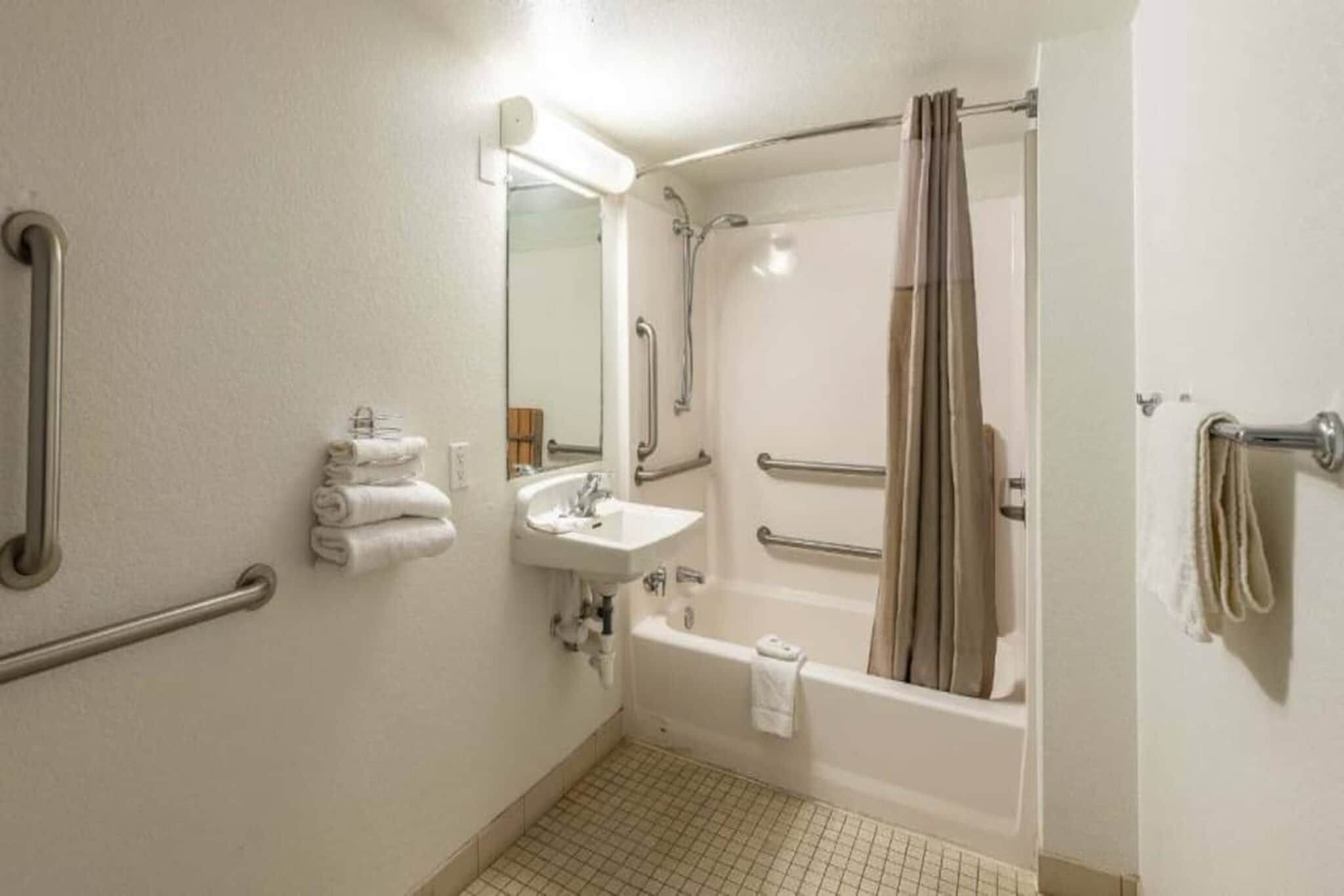 Un baño de hotel estándar con lavabo, espejo, inodoro y bañera.