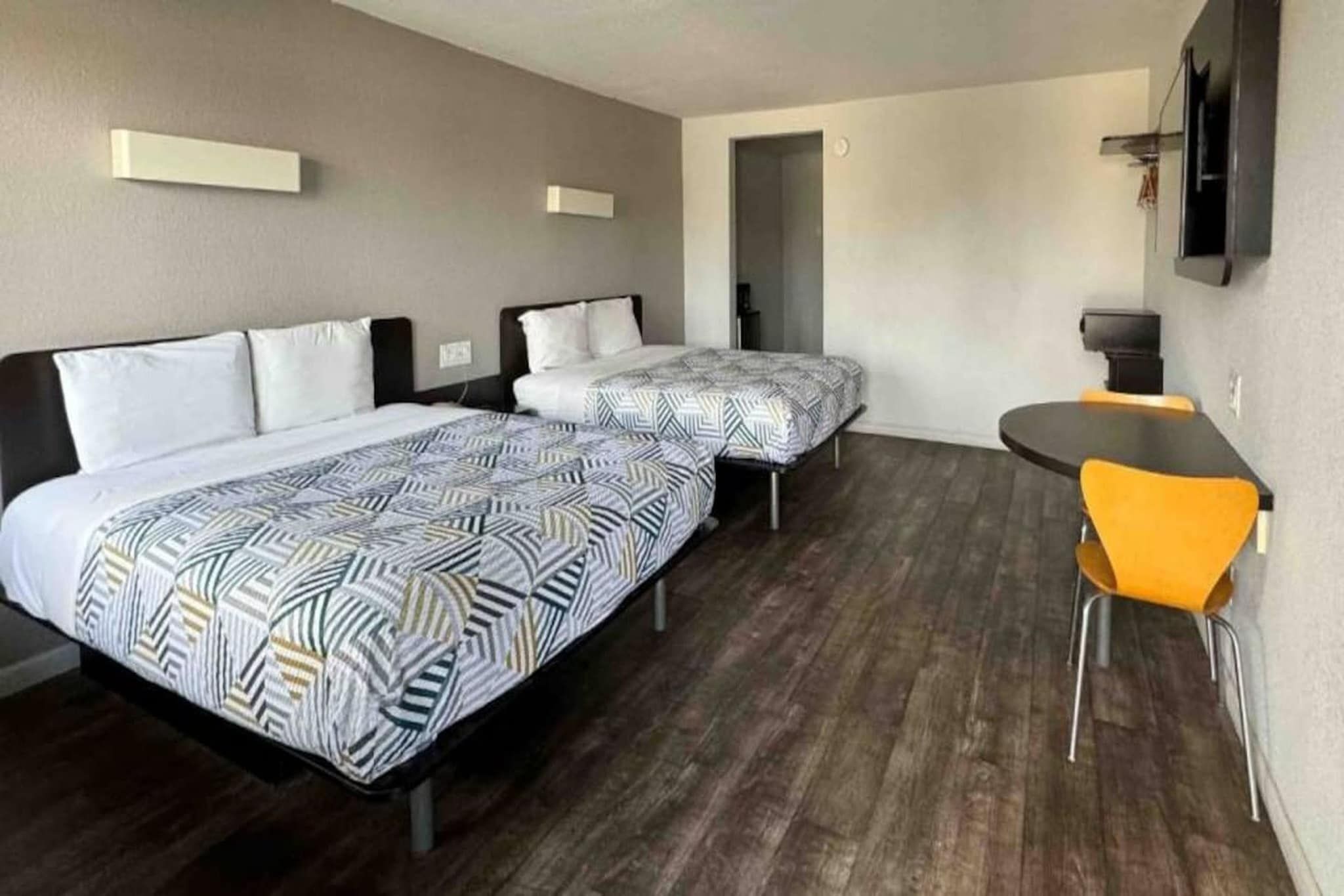 Ein Hotelzimmer mit zwei Betten, einem Schreibtisch und einem Sessel.