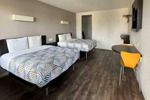 A hotel room with two beds, a desk, and a chair.