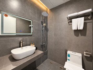 Un baño moderno con un espejo grande, un lavamanos, una ducha y un inodoro.