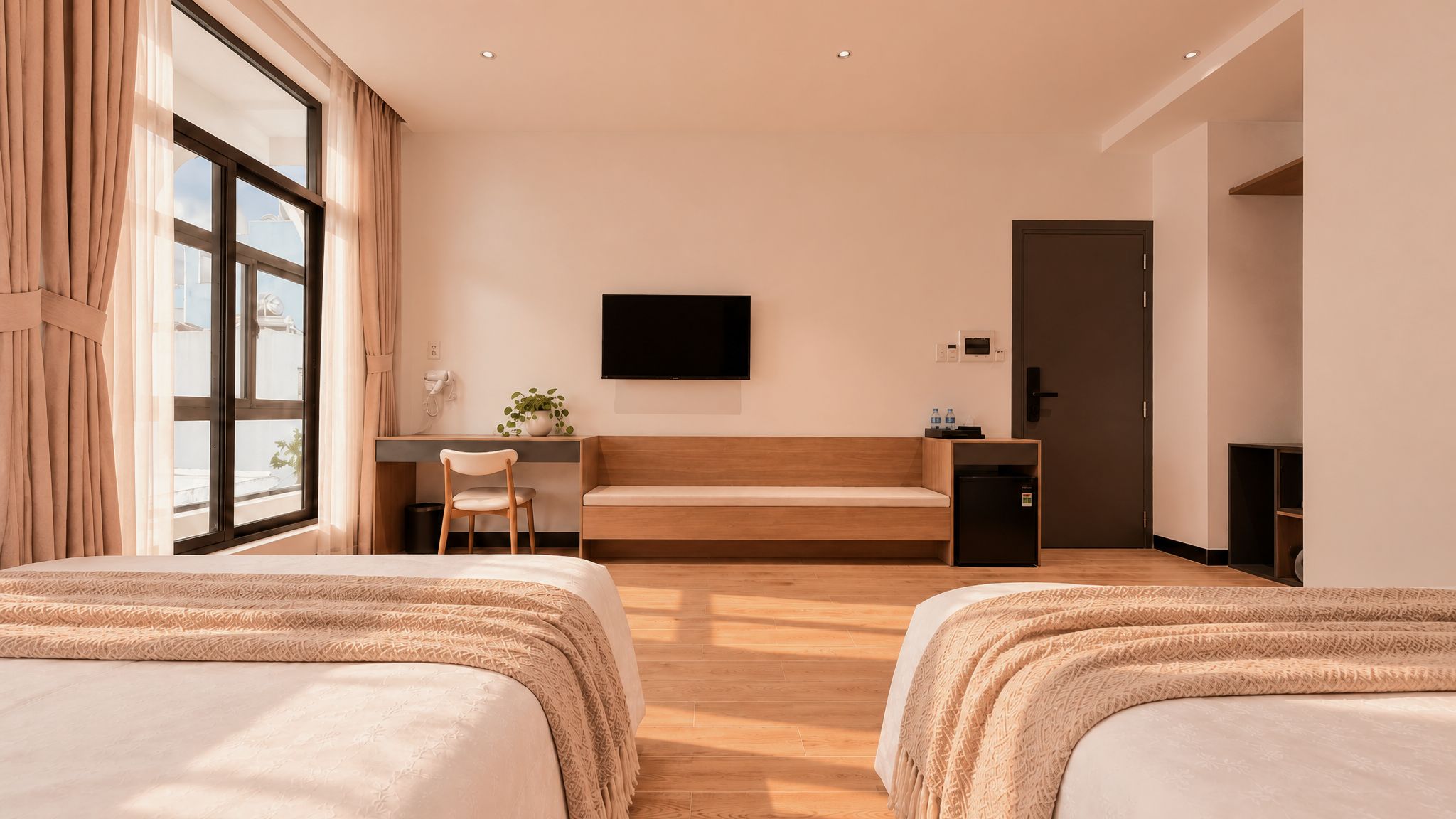Habitación de hotel con dos camas, un escritorio, un televisor y una pequeña kitchenette.