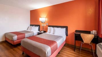 Quarto de hotel com duas camas, uma escrivaninha e uma cadeira.