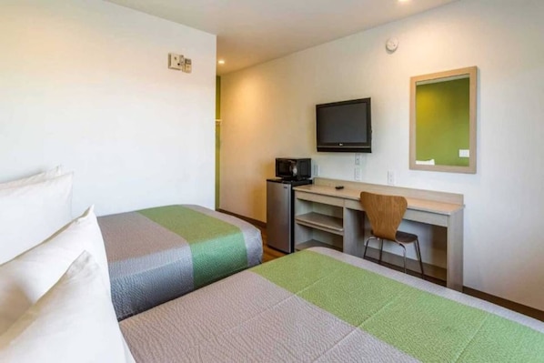 Habitació d'hotel amb dos llits, una taula, una cadira, una televisió i un mirall.