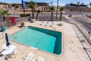 Una piscina rectangular amb una zona enrajolada al voltant, envoltada per una tanca baixa de metall blanc.