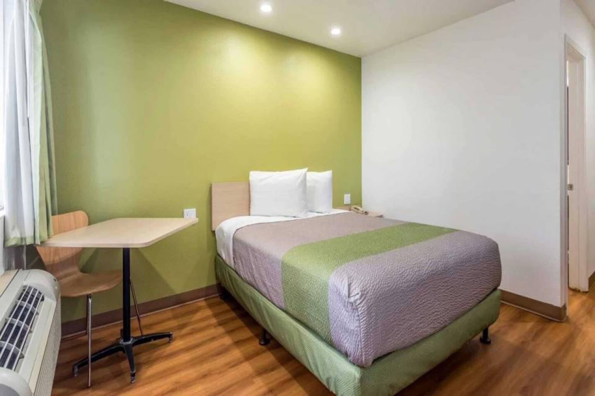 Ein Hotelzimmer mit einem Bett, einem kleinen Tisch und einer Klimaanlage.