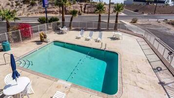 A rectangular swimming pool with a tiled deck, surrounded by a low white metal fence.