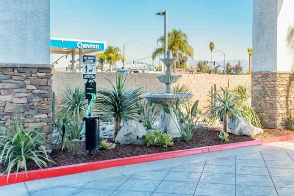 A Chevron gas station with a pet waste station, a fountain, and landscaped areas with cacti and succulents.