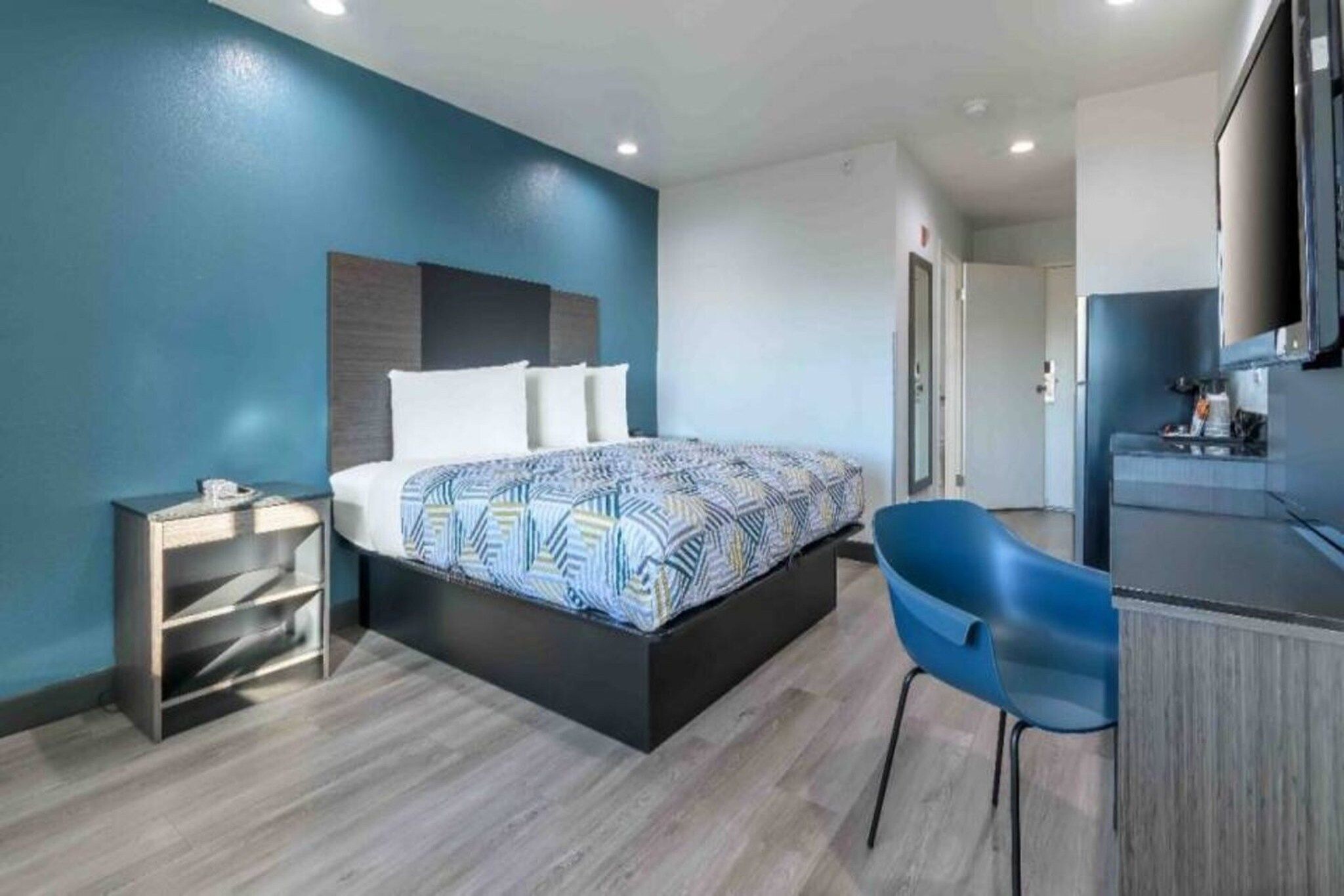 Une chambre d’hôtel moderne, équipée d’un lit, d’un bureau et d’une chaise.
