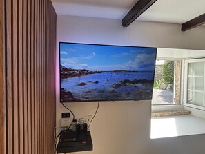 Televisor fixat a la paret amb una imatge de paisatge costaner.