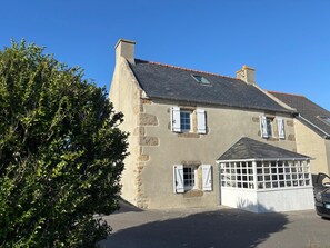 A two-story stone building with a sloped roof and a garage with a glass door. - Just 5 meters from the sea—a charming Breton house. (Porspoder)