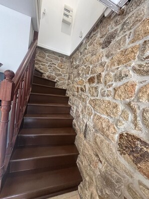Una escala amb baranes de fusta i parets de pedra.