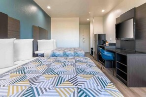 Una habitació d'hotel amb un llit, una taula de treball, una cadira i un televisor.