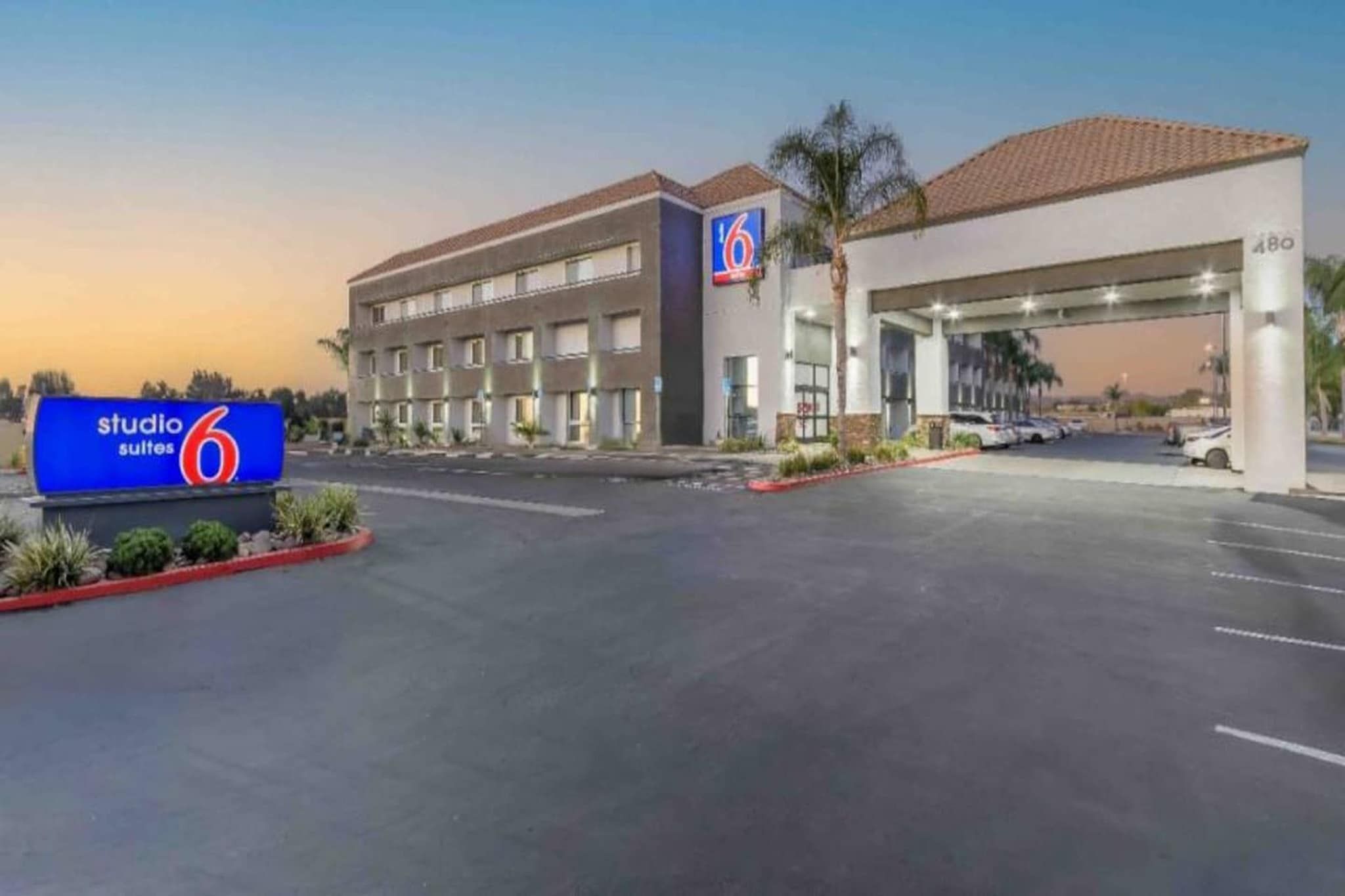 A hotel with a large parking lot, a '6' sign, and a 'studio' sign.