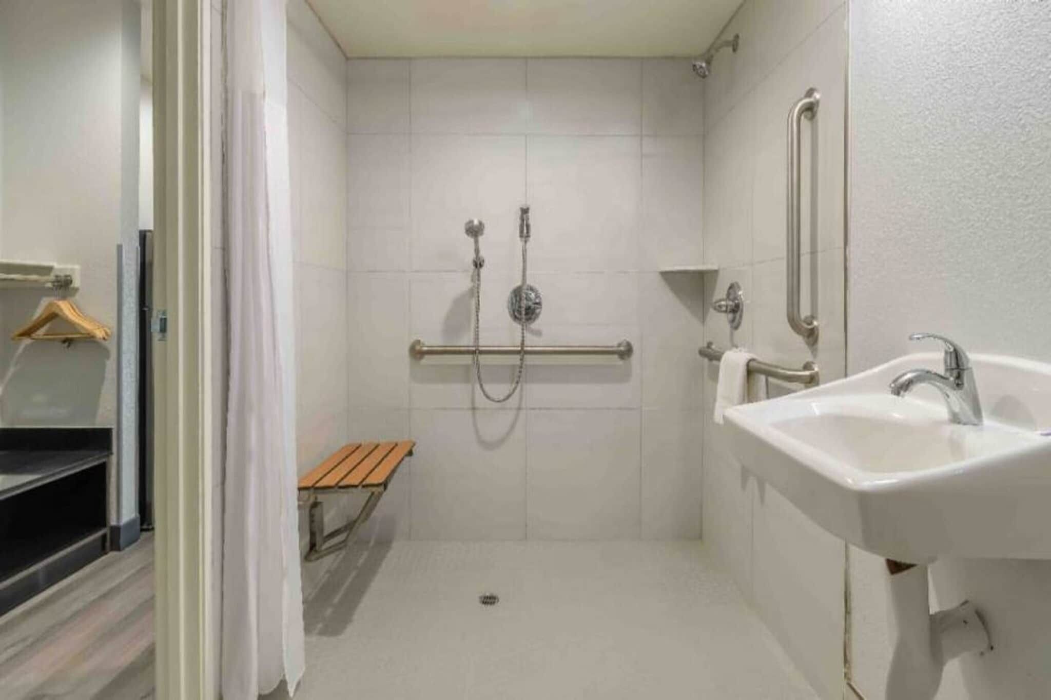 Une petite salle de bain fermée, équipée d’une douche, d’un banc et d’un lavabo.