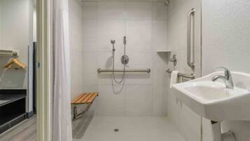 Une petite salle de bain fermée, équipée d’une douche, d’un banc et d’un lavabo.