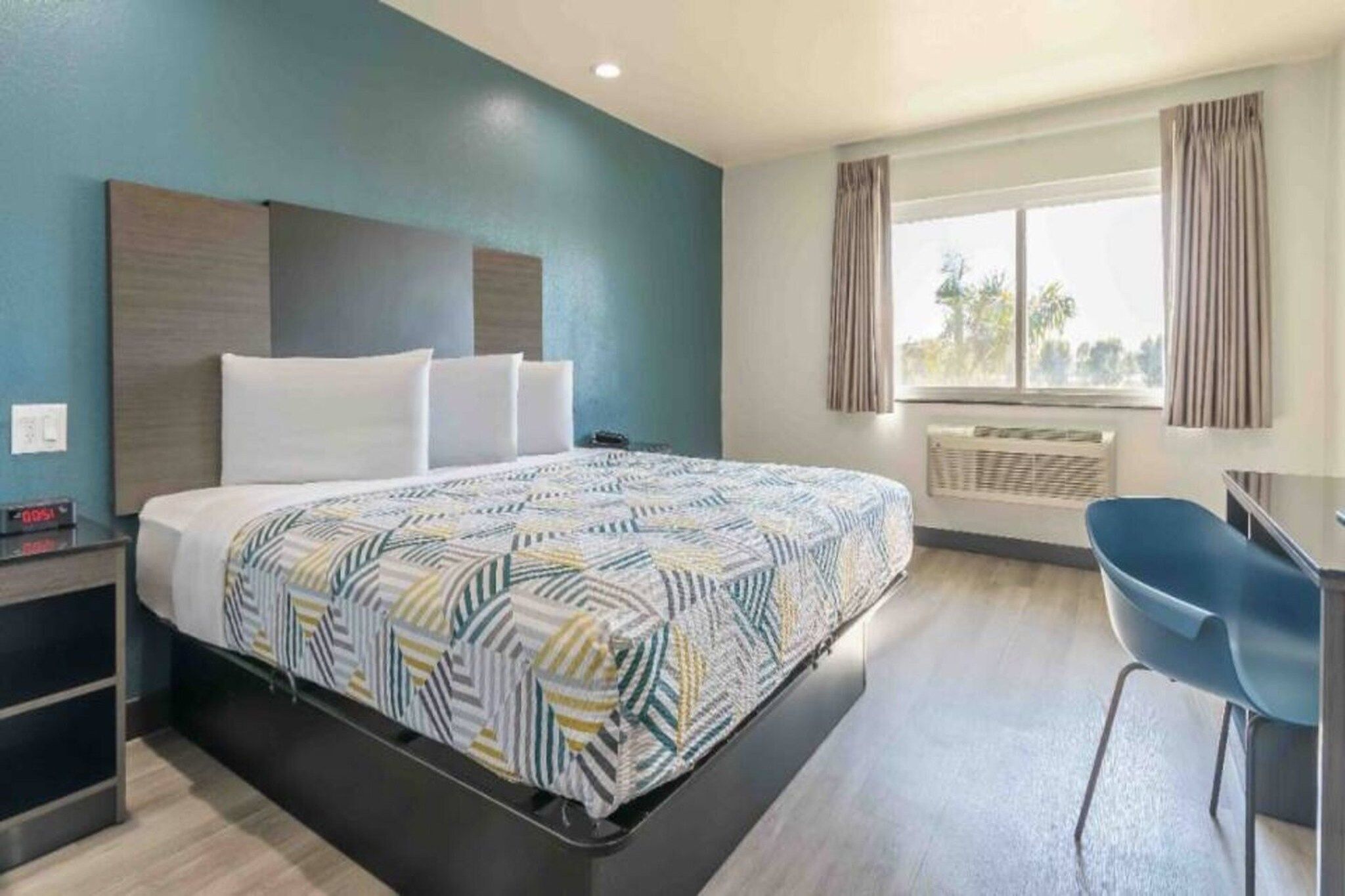 A hotel room with a bed, a desk, and a chair.