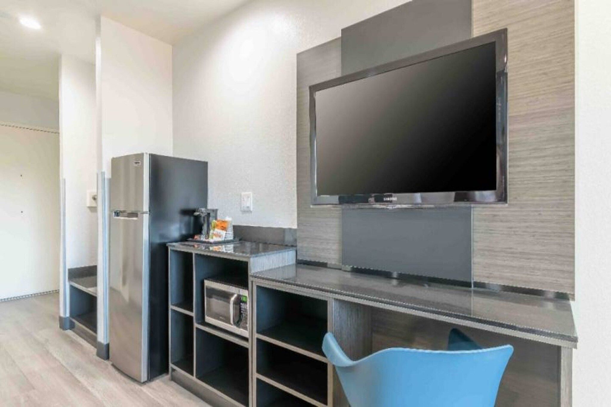 Eine Küchenzeile mit Kühlschrank, Mikrowelle und einem wandmontierten Flachbildfernseher.