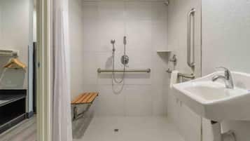 Une salle de bain avec une douche, un banc et un lavabo.