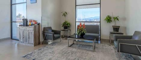 A modern lobby with a reception desk, seating area, and large windows offering a view.