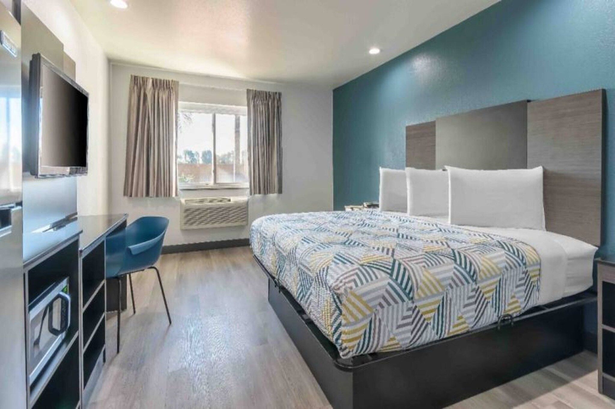 A hotel room with a bed, a TV, a desk, and a chair.