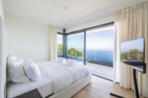 A bedroom with a bed, a TV, and a balcony with a view of the sea. - Exceptional Penthouse With Panoramic Terrace (Roquebrune-Cap-Martin)