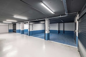 Eine Parkgarage mit mehreren Stellplätzen, die jeweils ein blau-weißes Farbschema und Deckenbeleuchtung aufweisen.