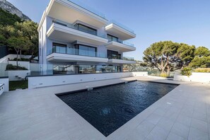 Ein modernes, mehrstöckiges Gebäude mit einem Schwimmbad im Vordergrund.