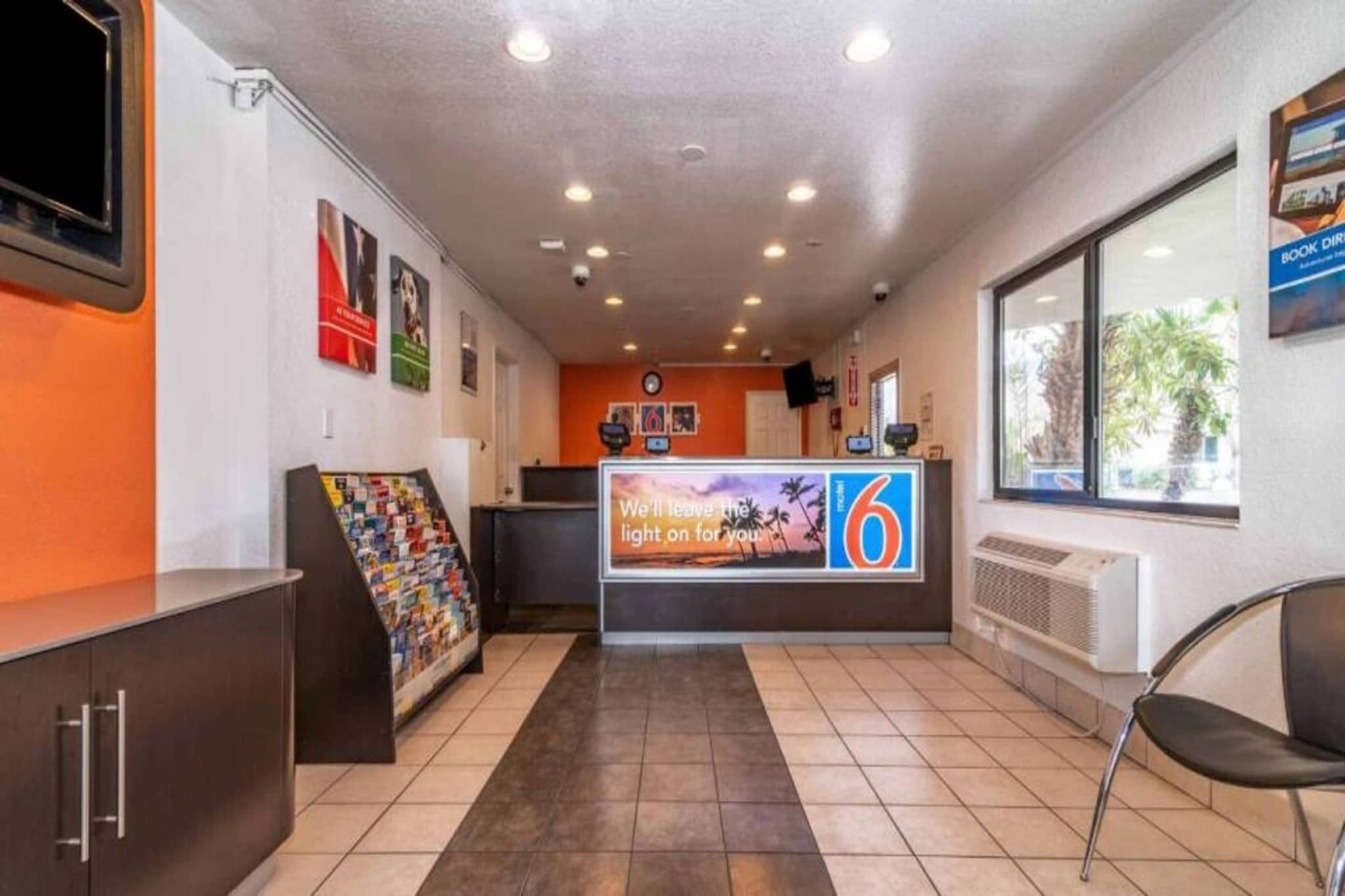 Uma área de recepção com balcão, porta-revistas e janela com vista.